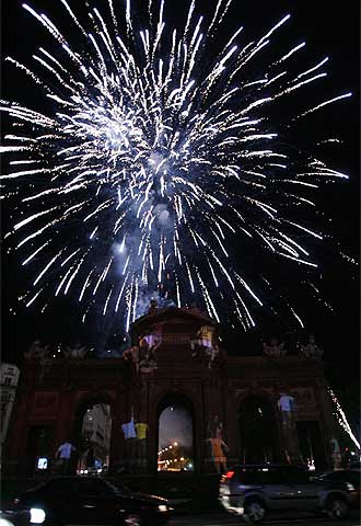 Aspecto de la Puerta de Alcalá, iluminada con imágenes proyectadas por focos de luz y fuegos artificiales