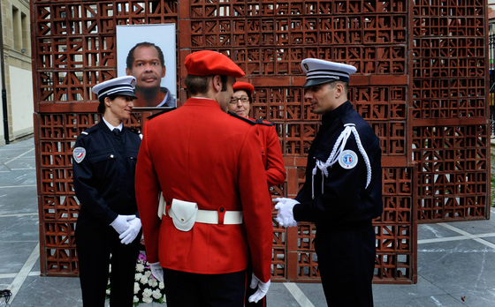 Agentes de la policía francesa y de la Ertzaintza conversan delante de una fotografía de Jean-Serge Nérin, policía galo asesinado por ETA. El Parlamento vasco ha rendido homenaje a Nérin.