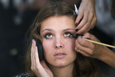 Una modelo habla por un teléfono móvil mientras es maquillada en la Cibeles Fashion Week de Madrid
