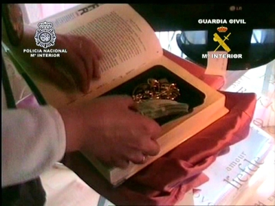 Un agente muestra piezas arqueológicas ocultas en un libro.