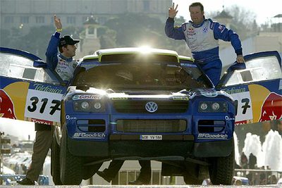 El piloto estadounidense Robby Gordon y su copiloto alemán Dirk Von Zitzewitz saludan al dejar Barcelona.