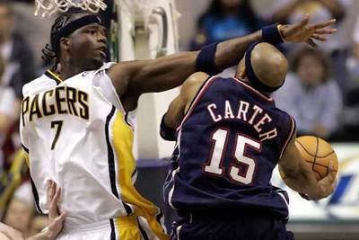 Jermaine O'Neal, de Indiana, bloquea la entrada a canasta de Vince Carter, de Nueva Jersey.