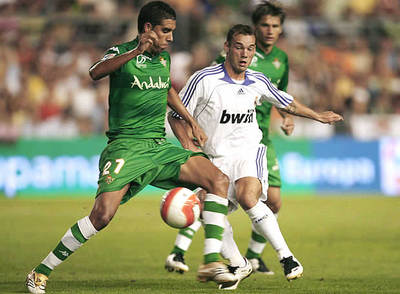 El bético Juande protege el balón ante el acoso de Sneijder