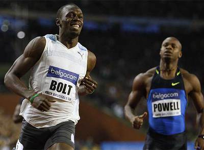 Bolt cruza la meta ante la atenta mirada de su compatriota Powell.