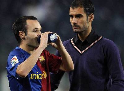 Iniesta se refresca en la banda junto a Guardiola.