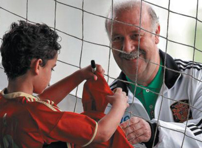 Del Bosque firma una gorra a un niño tras un entrenamiento de la selección