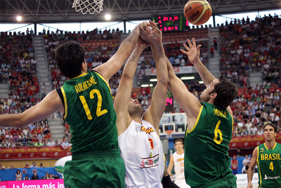Felipe Reyes lucha por capturar un rebote entre dos rivales brasileños.