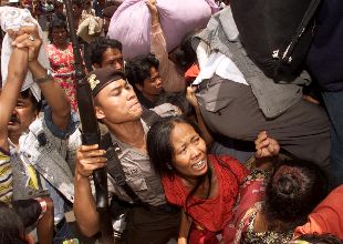 Un policía indonesio, entre refugiados madureses que intentan subir ayer a un barco para huir de Borneo.
