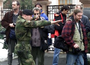 Un policía militar dispersa ayer a varios periodistas ante la residencia del ex presidente Slobodan Milosevic, en Belgrado.