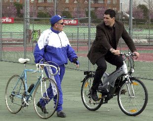 Miguel Induráin conversa con un aficionado, mientras pasea con la bicicleta motorizada.