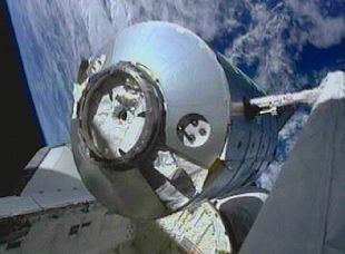 Un brazo mecánico teledirgido desde el  Discovery  durante la maniobra de acomplamiento del contenedor Leonardo a la ISS.