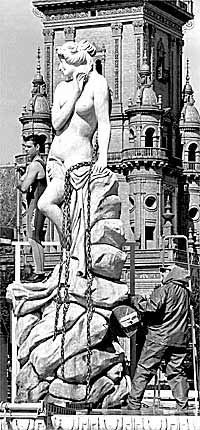 Dos empleados revisan la estatua instalada en la Plaza de España.