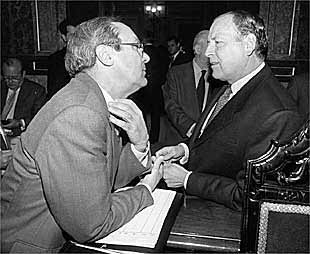 Pedro Bujidos (a la izquierda) conversa con el alcalde durante un pleno municipal.