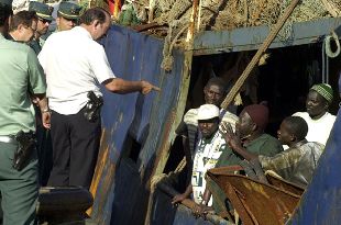 Policías y guardias civiles hablan con algunos de los inmigrantes del  Ashva , a su llegada al puerto de Santa Cruz.