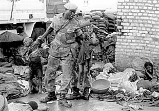 Un soldado retira dos niños muertos de entre decenas de cadáveres para preparar una fosa común, el 22 de abril de 1995.