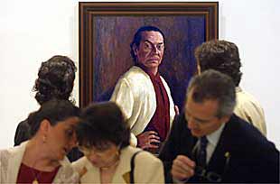 Visitantes de la exposición sobre Antonio, junto a un retrato del bailarín.