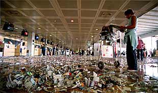La terminal B del aeropuerto de El Prat, ayer, llena de papeles.