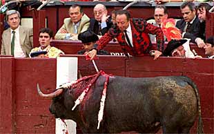 José Tomás, en el callejón, después de oír los tres avisos, contempla cómo quitan el estoque al toro para apuntillarlo.