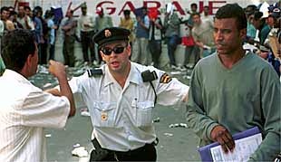 Un policía saca a dos inmigrantes de la cola ante las oficinas del Ministerio de Trabajo en Almería.