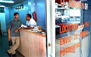 Tras el mostrador, hablando con un cliente, Mohamed Flifcam, que lleva 10 años regentando ese locutorio en Crevillent.