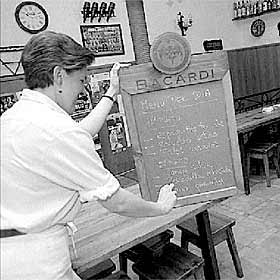 Una empleada de un restaurante escribe en la pizarra los platos del menú del día.