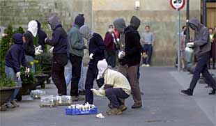 Un grupo de encapuchados prepara bombas incendiarias en una calle de Bilbao para sus acciones de violencia callejera.