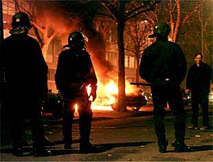 Un grupo de policías observa un coche ardiendo en la localidad francesa de Estrasburgo.