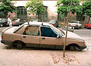 Uno de los coches abandonados y despojados de las ruedas en la calle de Santa Isabel.