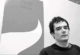 El joven diseñador gráfico Pablo Errea, ante el cartel anunciador de los  sanfermines,   obra suya.