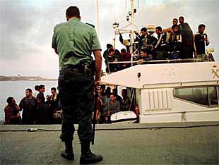 Un guardia civil vigila una patrullera en la que son trasladados inmigrantes.