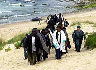 Inmigrantes subsaharianos son trasladados por la policía tras desembarcar en una playa de Tarifa.