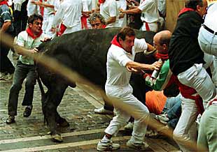 Un  miura  embiste sobre un montón de corredores en la curva de Mercaderes.