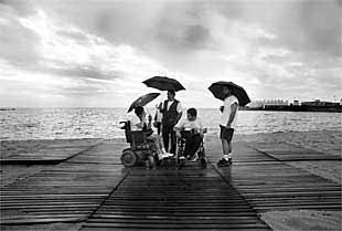 Voluntarios y discapacitados, ayer en la playa del Bogatell, en Barcelona. La tormenta de la noche anterior frustró el encuentro.