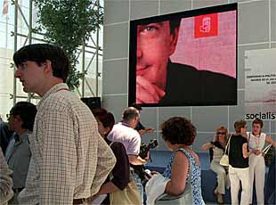 Delegados y fotógrafos, que hicieron un plante por problemas con la organización, ante un cartel de Zapatero.