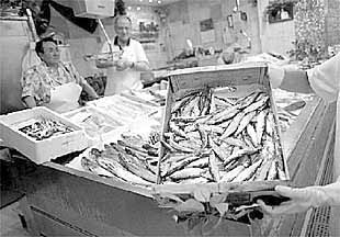 Una pescadera del mercado de La Bretxa muestra una caja de sardinas.