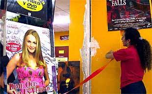 La empleada de un videoclub muestra una de las grietas surgidas en el local.