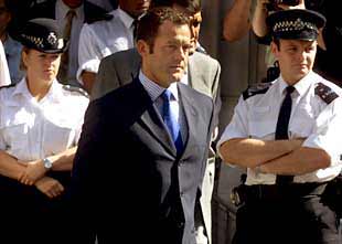 El que fuera mayordomo de Lady Di, Paul Burrell, abandona el tribunal rodeado por la policía.