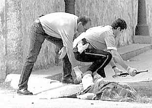 Dos    ertzainas  recogen la escopeta utilizada en el crimen junto al cuerpo sin vida del autor de los disparos.