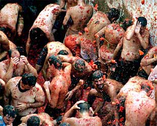 Los participantes en la  Tomatina  se protegen de los impactos.