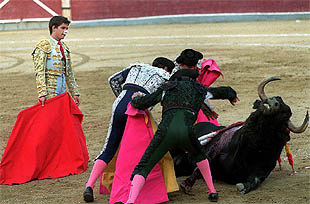 El Juli observa a su cuadrilla, que intenta levantar al tercer toro en una de sus numerosas caídas.