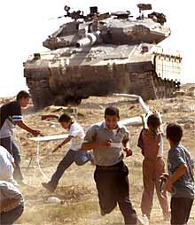 Un grupo de palestinos huye ante un carro de combate israelí en Gaza.