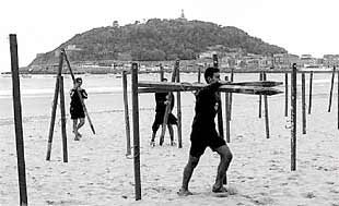 Unos jóvenes retiran, ayer, los toldos de la playa de la Concha.