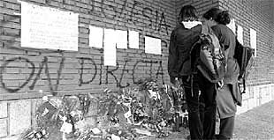 Dos jóvenes ante el lugar donde murió Alejo Aznar, en los soportales de la parroquia de Romo.