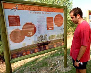 Un excursionista, ante un panel explicativo con las rutas propuestas para la observación de aves en El Pardo.