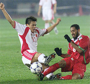 El chino Li Tie (a la izquierda) disputa el balón al omaní Al harbi en el partido de ayer en Shenyang.