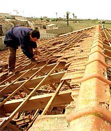 Un hombre inspecciona los daños del pedrisco en un tejado de la pedanía de Valverde, en Elche.
