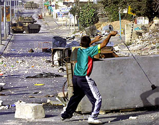 Un adolescente palestino lanza piedras con una honda contra tanques israelíes en Belén, Cisjordania.