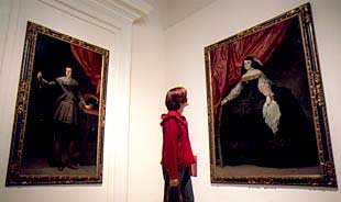 Una visitante, entre el retrato de    Don Juan González Uzqueta  (anónimo madrileño), a la izquierda, y el de    Doña María de Vera,  de Carreño de Miranda.