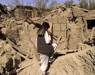 Un combatiente de la Alianza del Norte camina sobre las ruinas de una casa destruida por los bombardeos estadounidenses en Ghanee Jil.