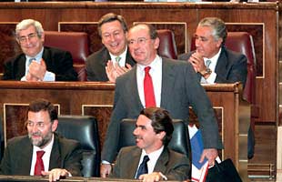 Rato, de pie tras Aznar y Rajoy, recibe los aplausos de su grupo parlamentario durante la sesión de control al Ejecutivo en el Congreso.